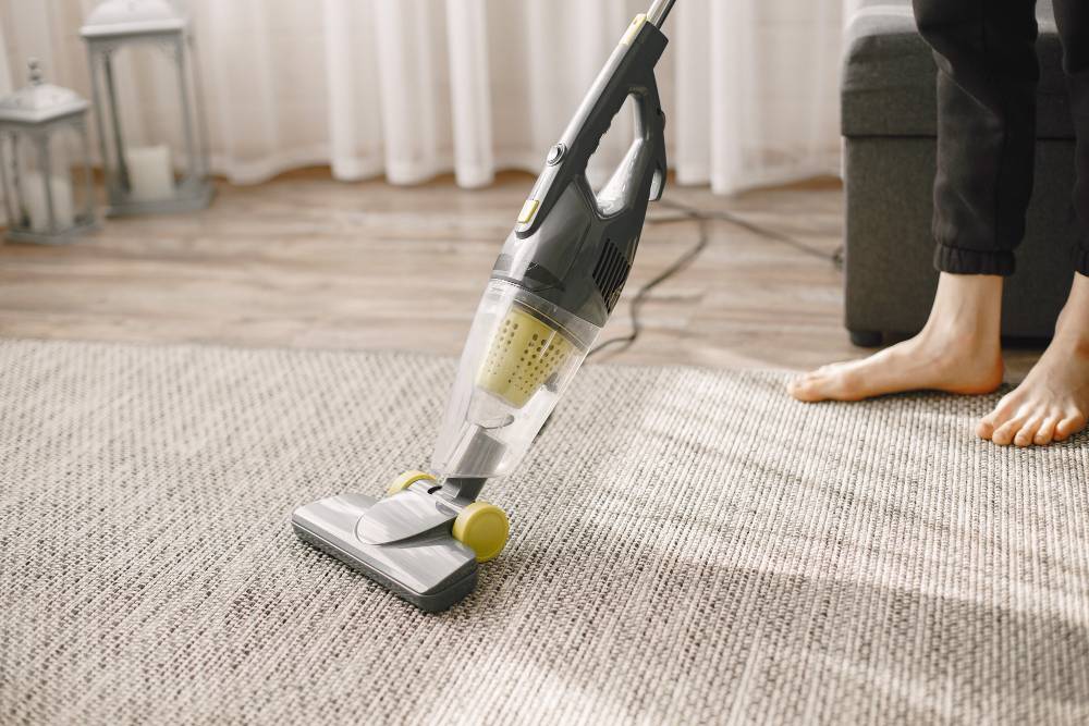 Person vacuuming a carpet in a living room with bare feet.
