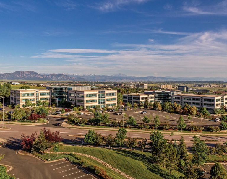 Office buildings with parking lot and mountain backdrop.